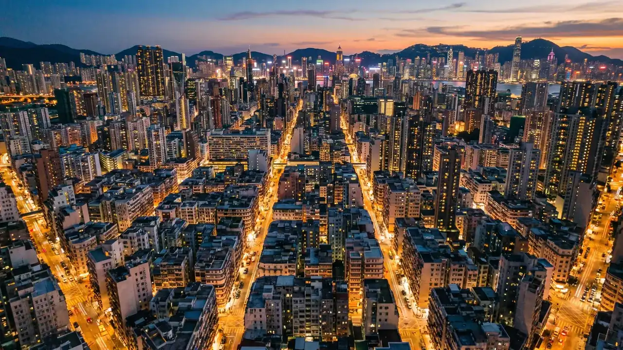 黃昏時分密集城市街區的鳥瞰圖，燈光正在亮起